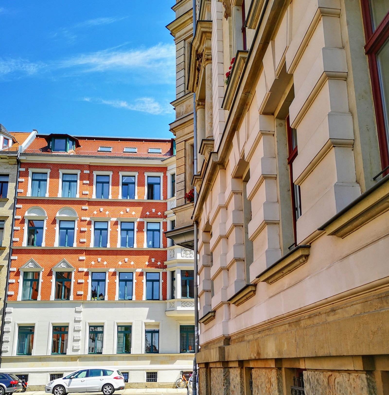 Blick die Fassade eines Gründerzeithauses in Leipzig entlang, im Hintergrund ein Klinkerbau